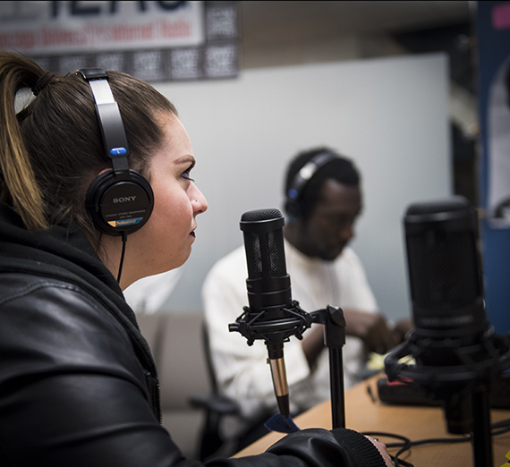 Student close to a microphone recording a podcast.