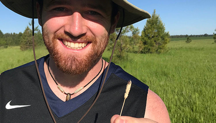 Harrison Eagle holds wheat in his hand.