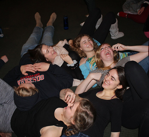 A cluster of students laying on the floor in laughter.