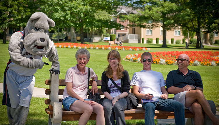 A Gonzaga family sitting on a bench on campus with GU's mascot, Spike