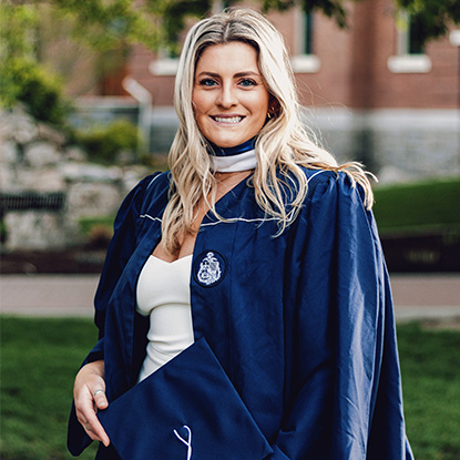Graduating college student poises in robes