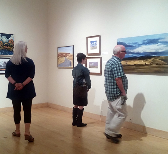 People admire paintings hanging on walls.