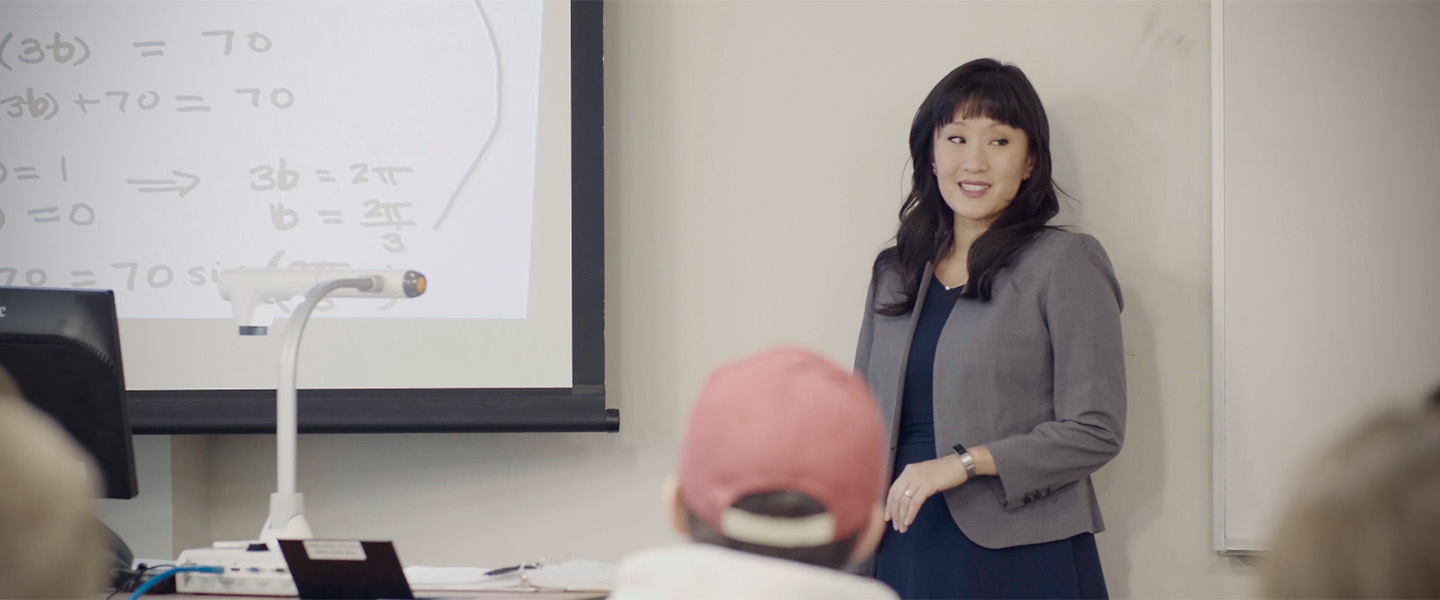 Bonnie Dichone stands in front of a classroom teaching math.