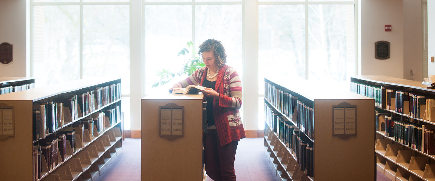 Student stands by book cases in law school 