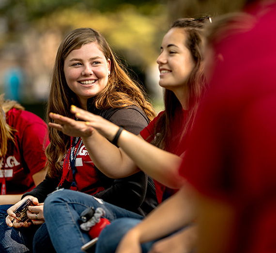 students sitting in grass smiling