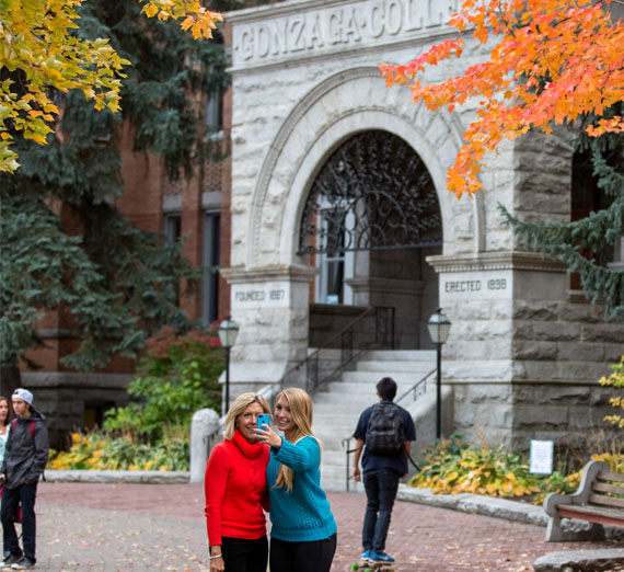 student and parent take selfie in front of college hall 