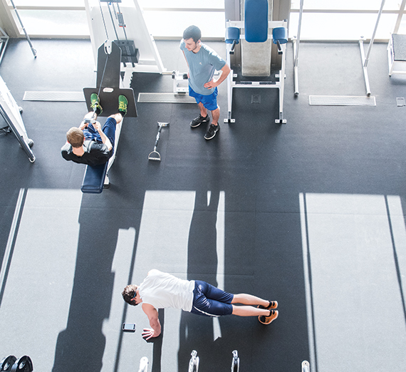 Three GU students lift weights in the weight room