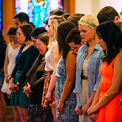 Students standing together in prayer.