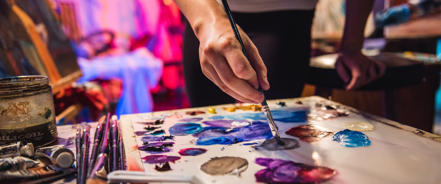 A student uses a paintbrush to mix paint