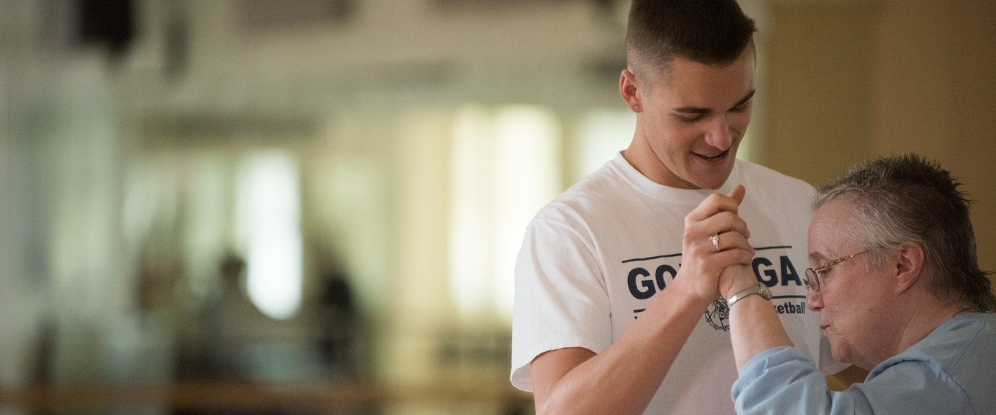 A student dances with an elderly woman who has parkinsons