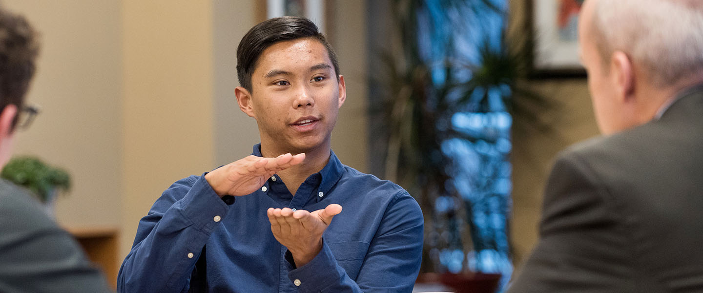 Student speaking with professionals at business breakfast.