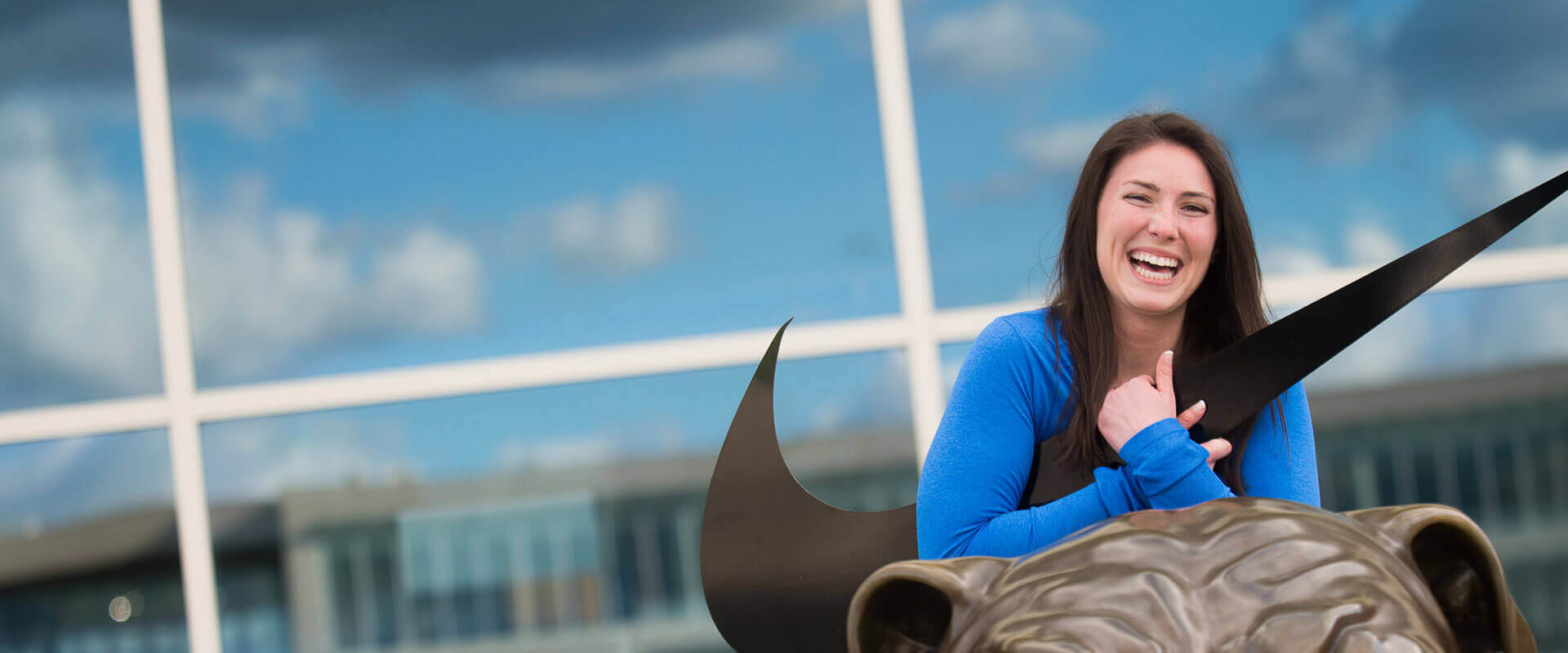 Sara Wendland hugs the Nike logo while sitting on the Bronze Bulldog