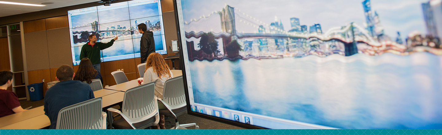 Large computer monitor on the right sdie. People in the background on the left site.