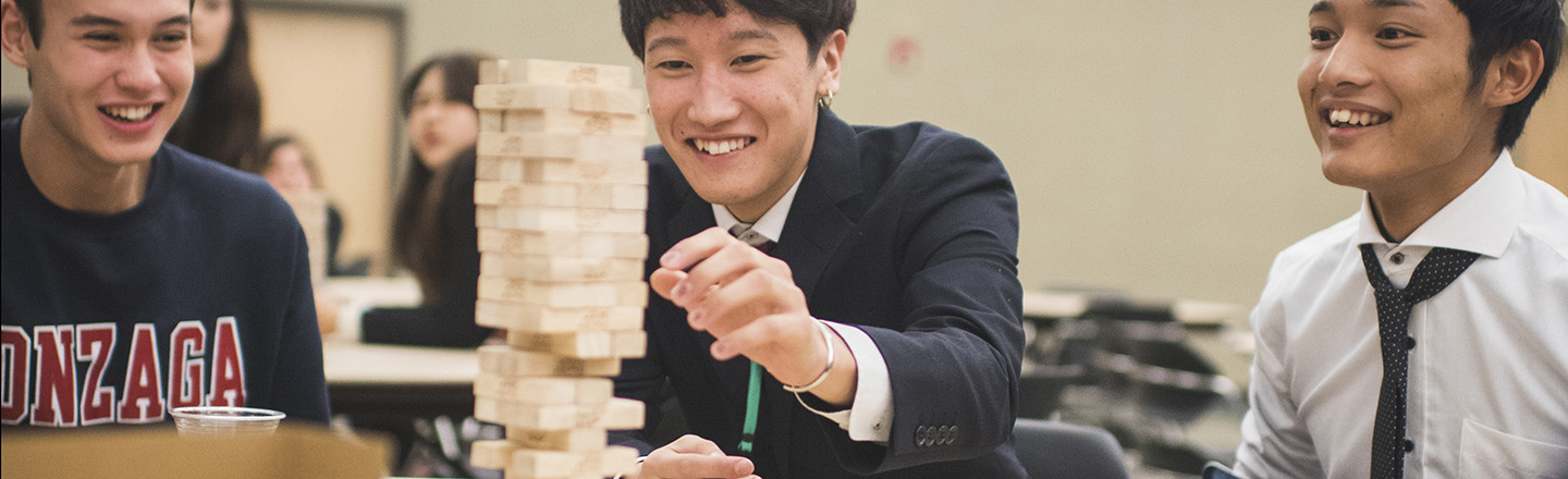 Three students playing game while sitting at a table.