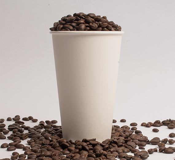 Coffee beans fill a coffee cup. 