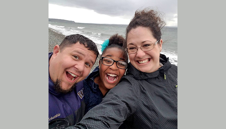 happy parents with adopted older child on the beach