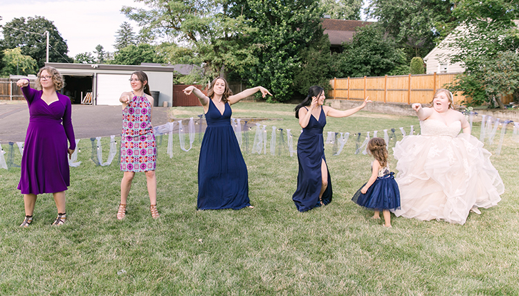 bride with wedding party dancing in the grass