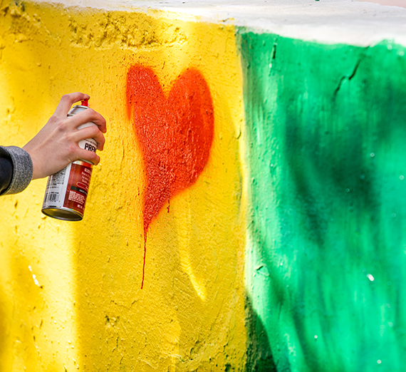 yellow and green spraypaint on a wall with a red heart