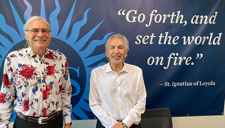 two gentlemen in front of banner reading go forth and set the world on fire by Ignatius