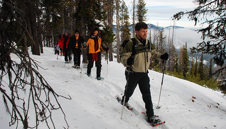 A group of people snowshoe on a trail along a ridge at Mt. Spokane State Park.