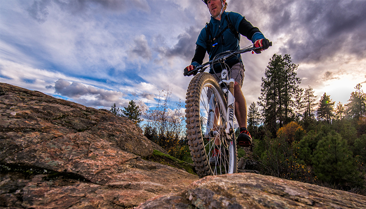A mountain biker crosses a rocky section of trail.