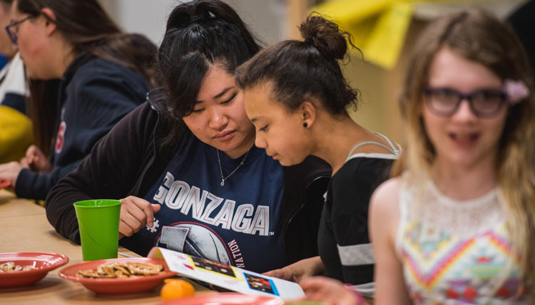female college student talks with younger primary student