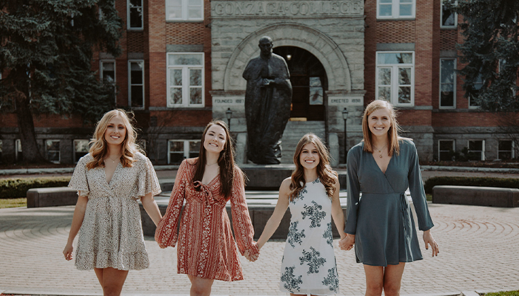 four girls in dresses in front of Gonzaga's College Hall
